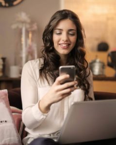 A woman using her phone and laptop