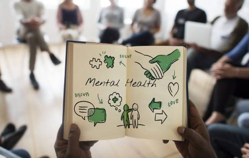 A person holding a notebook with illustrations on mental health in green color